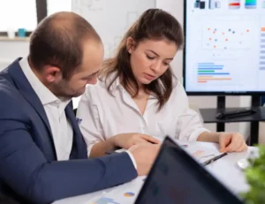 Dos profesionales analizando informes y gráficos impresos en una mesa de oficina